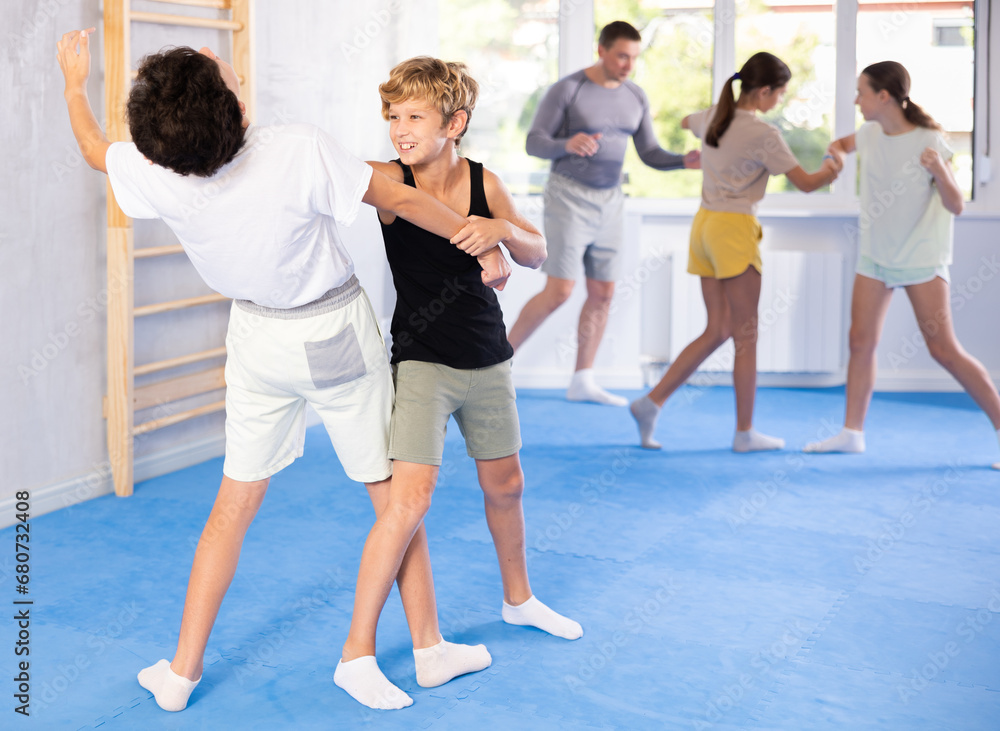 Two boys practicing self-defense techniques in group at gym