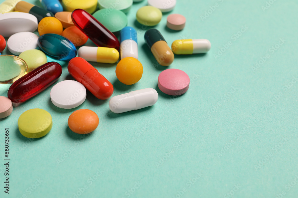 Many different pills on turquoise background, closeup. Space for text Many different pills on turquoise background, closeup. Space for text