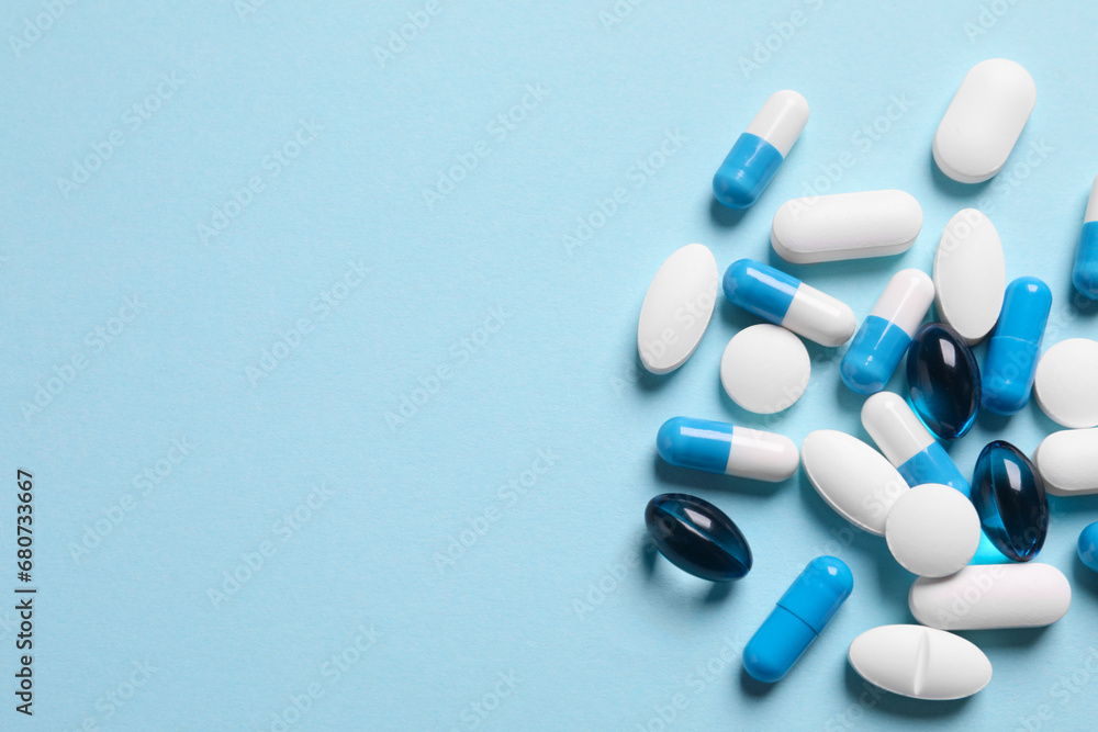Many different pills on light blue background, flat lay. Space for text Many different pills on light blue background, flat lay. Space for text