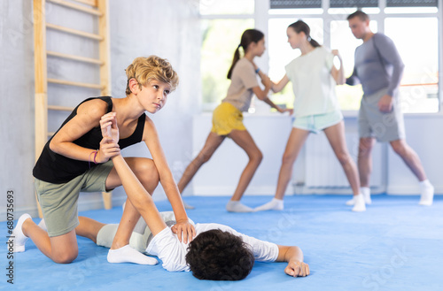 Children boy and girl partner in sparring practice technique practicing basic attacking movements and maneuvers. Class self-defense training in presence of experienced instructor. Wrestling as an art