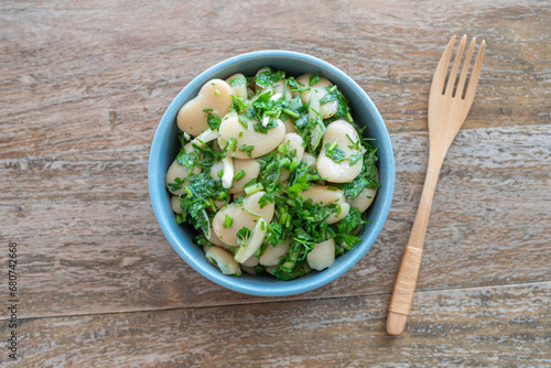 Lima Bean Salad with herbs and garlic in ceramic plate over wooden background.
