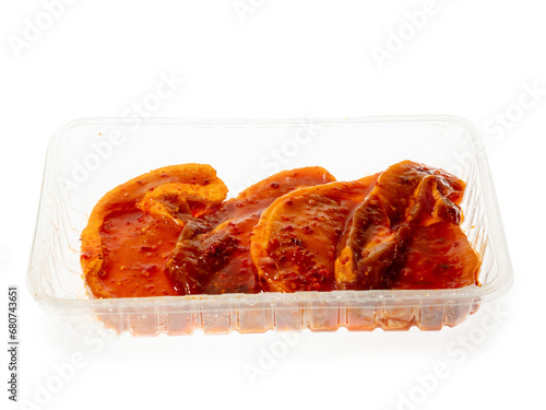 Pork chops in Asian style spicy marinade in plastic tray. White background. Popular meat product for a barbeque. Simple food. © mark_gusev