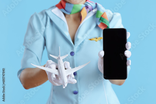Flight attendant woman on blue showing smartphone blank screen photo