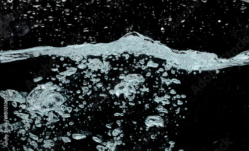 Ocean wave splash into surface underwater and many bubbles water. Drinking soda water flush air bubble. Black background isolated freeze element