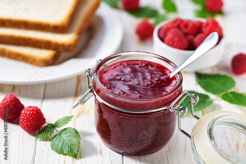 Plate with slices of bread and delicious raspberry jam on wooden table. Bread and raspberry homemade jam on wooden table