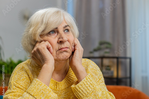Portrait of sad stressed senior grandmother woman sitting at home looks pensive thinks over life concerns, suffers from unfair situation. Problem crisis depression feeling bad sick ill annoyed burnout