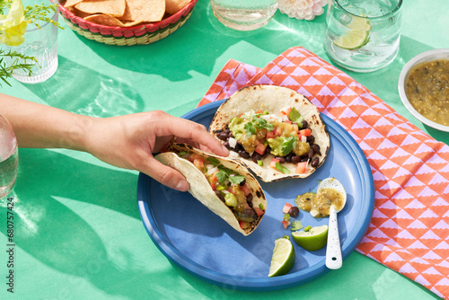 Fotografie Vividly colorful Mexican fare with hand lifting taco