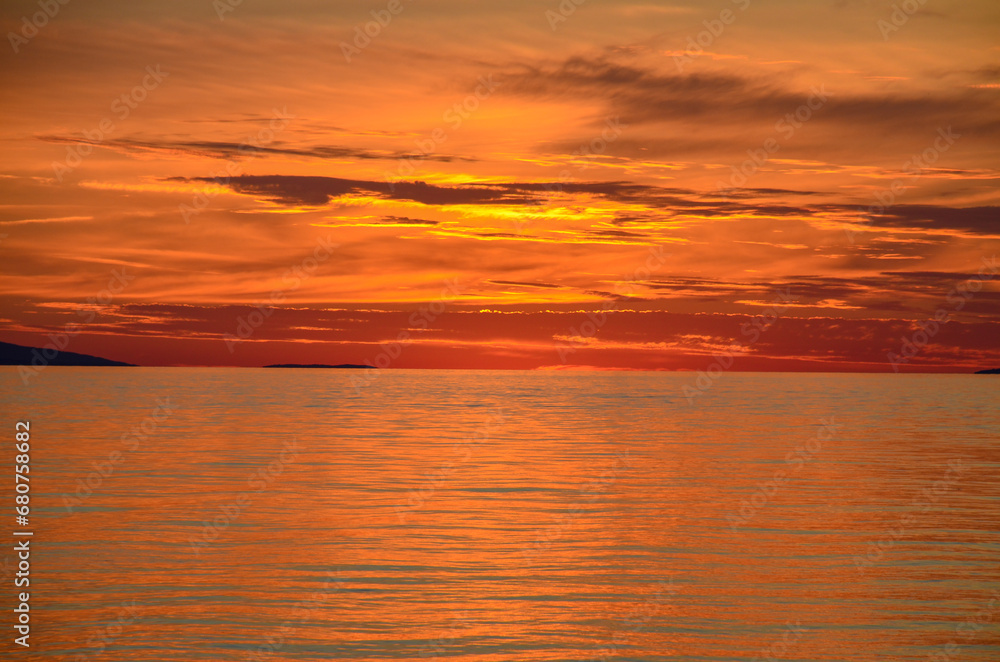 Obraz premium Beautiful orange sky and clouds above the sea after sunset. Peaceful waves on the sea in the evening.