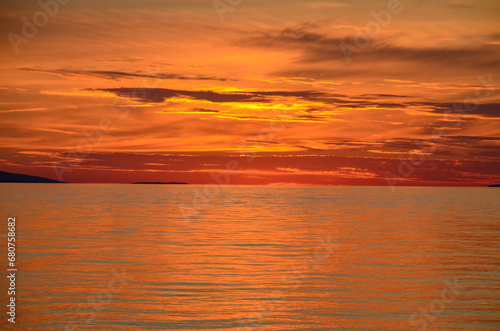 Beautiful orange sky and clouds above the sea after sunset. Peaceful waves on the sea in the evening.