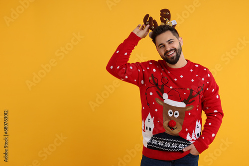 Wallpaper Mural Happy young man in Christmas sweater and reindeer headband on orange background