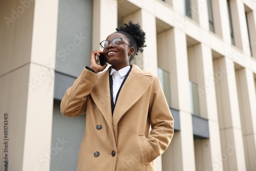 Happy woman talking on smartphone outdoors, low angle view. Lawyer, businesswoman, accountant or manager