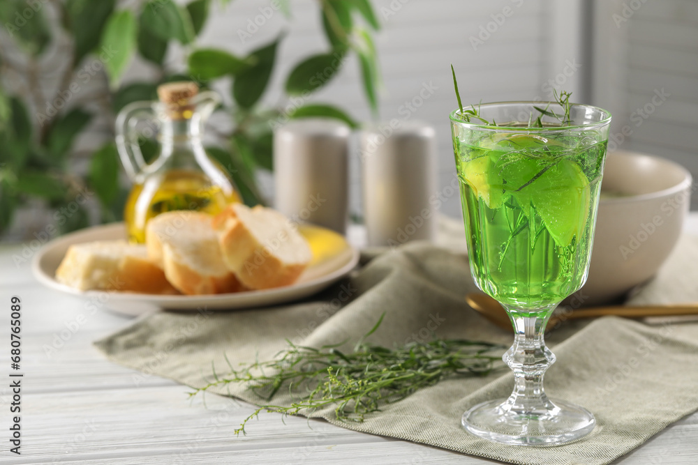 Delicious drink with tarragon in glass on white wooden table. Space for text
