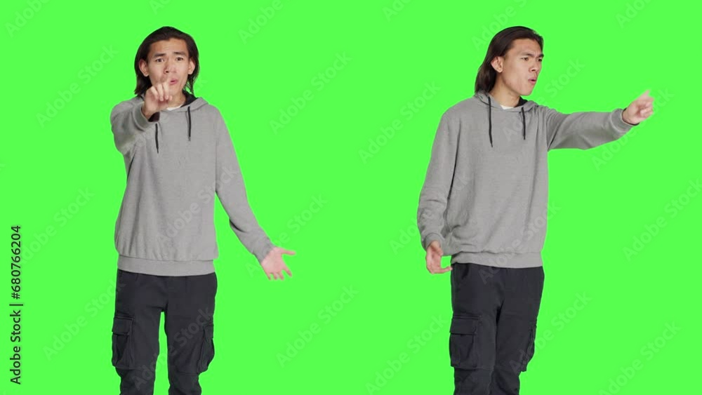 Young man showing no gesture in studio, expressing negativity and disagreement over isolated greenscreen backdrop. Asian male model being disappointed and disapproving with something. Young man showing no gesture in studio, expressing negativity and disagreement over isolated greenscreen backdrop. Asian male model being disappointed and disapproving with something.