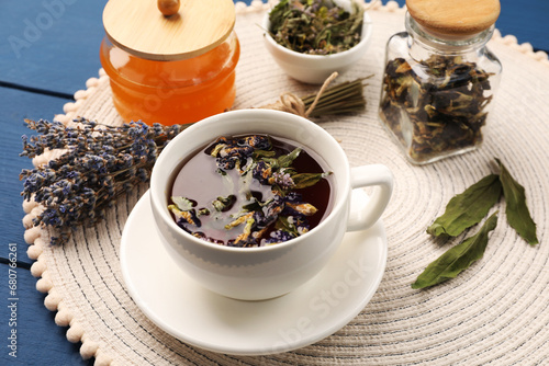 Billede på lærred Aromatic tea with different dry herbs and honey on blue wooden table, closeup