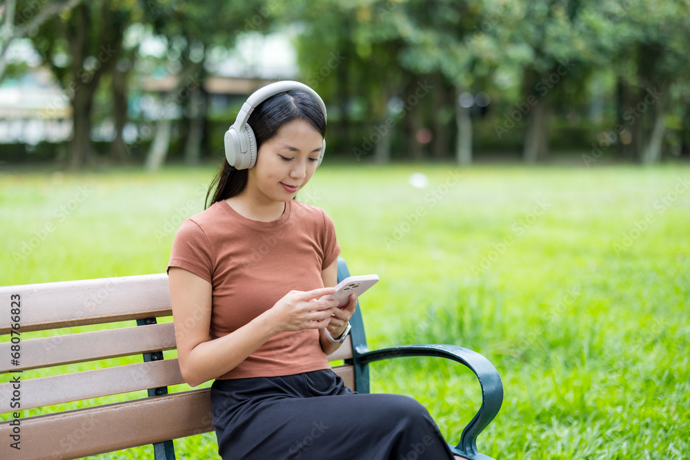 Obraz premium Woman listen to headphone and use of cellphone at park