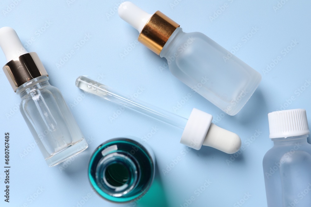 Bottles of cosmetic serum on light blue background, flat lay Bottles of cosmetic serum on light blue background, flat lay