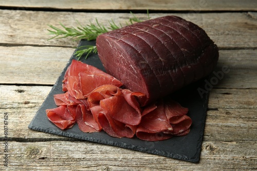 Tasty bresaola and rosemary on wooden table photo