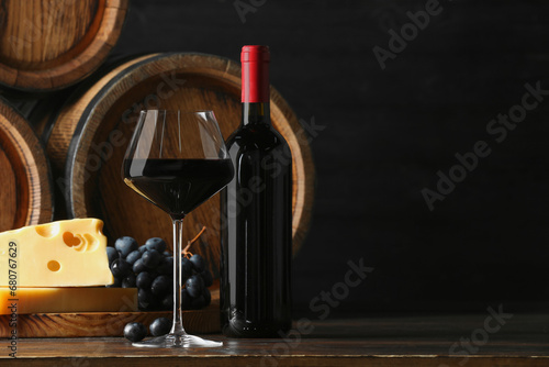 Delicious wine, wooden barrels, cheese and fresh grapes on table, space for text © New Africa
