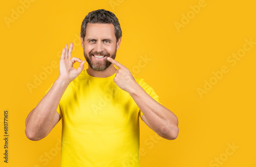 man pointing at teeth smile on background, copy space. man pointing at teeth smile in studio.