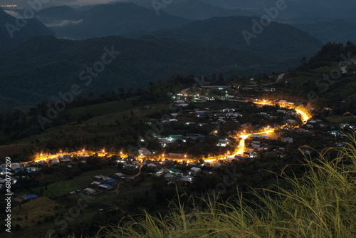 Path up the mountain at night with lights from villages along the road on both sides The village must be in the middle of a valley. There are forests and complete nature. © Yuttana