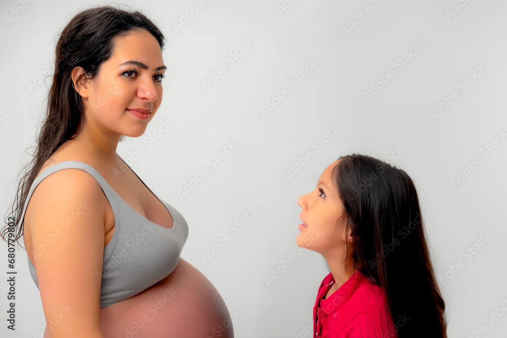 Portrait of a woman in advanced pregnancy opposite whom her young daughter is standing and looking at her Portrait of a woman in advanced pregnancy opposite whom her young daughter is standing and looking at her