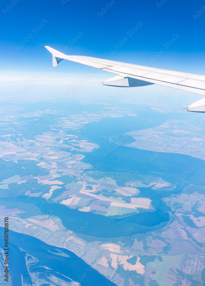 Aerial view from airplane window above green ground. View from the airplane window with beautiful clouds at sunrise Aerial view from airplane window above green ground. View from the airplane window with beautiful clouds at sunrise