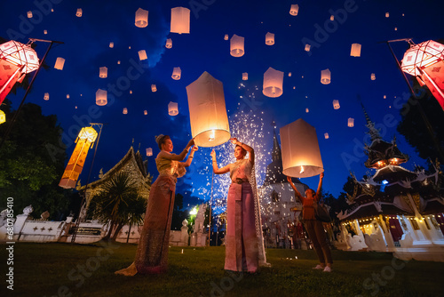 Young women releasing sky lantern into the night sky in yi peng festival. Floating lanterns ceremony or Yeepeng ceremony, traditional Lanna Buddhist ceremony in Chiang Mai, Thailand. lanterns at dusk photo
