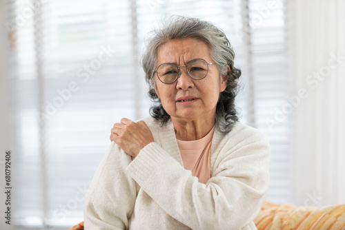 Asian Elderly senior woman with white hairs neck and shoulder pain and illness on sofa alone at home,Elderly Care and insurance Concept