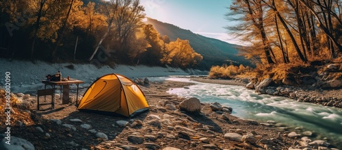 camping with a tent on the river bank with sunlight in the morning and clear river water and natural views