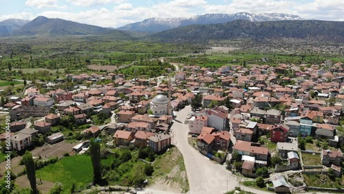 Scenic spring view from drone of Yesildag village with residential houses and mosque in green valley surrounded by mountains with peaks covered with snow, Turkey photo