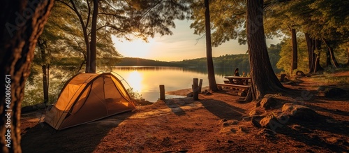 camping with a tent on the lake bank in early morning. morning sunlight touches against forest hill photo