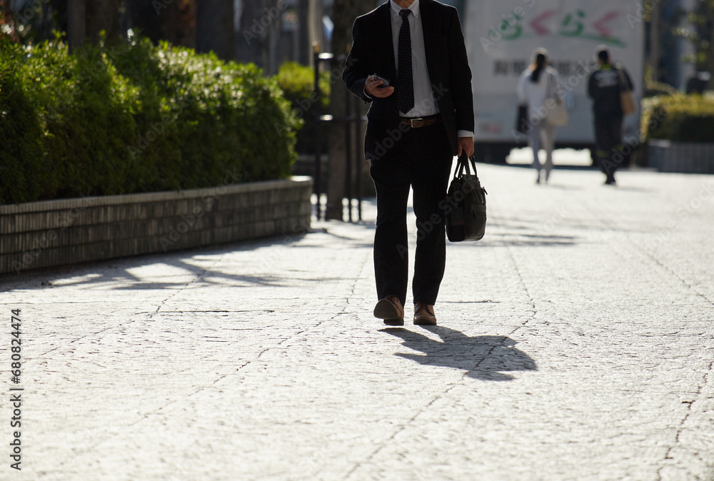 Obraz premium 朝の通勤時間の街で歩く男性サラリーマンの姿