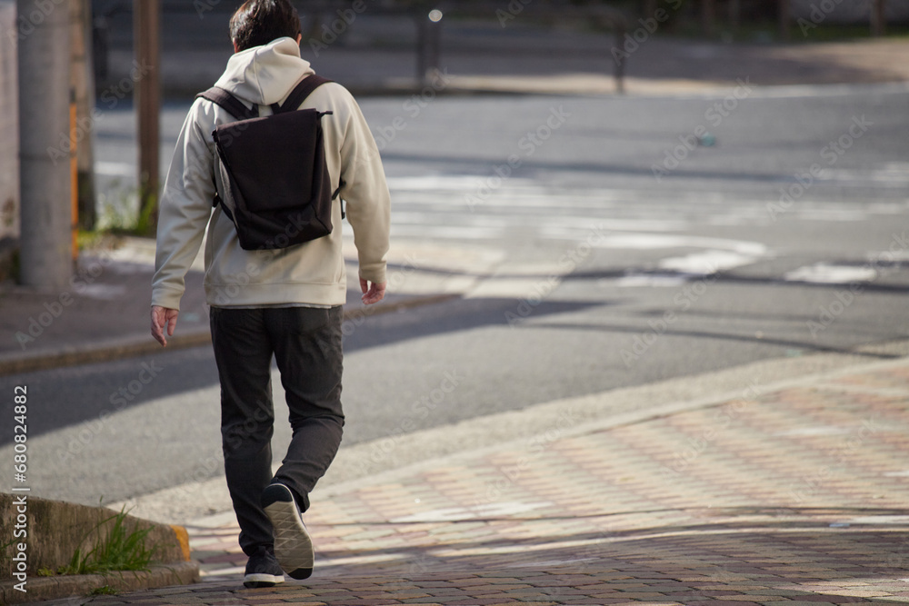 Fototapeta premium 冬の朝の繁華街で歩く一人の男性サラリーマンの後姿
