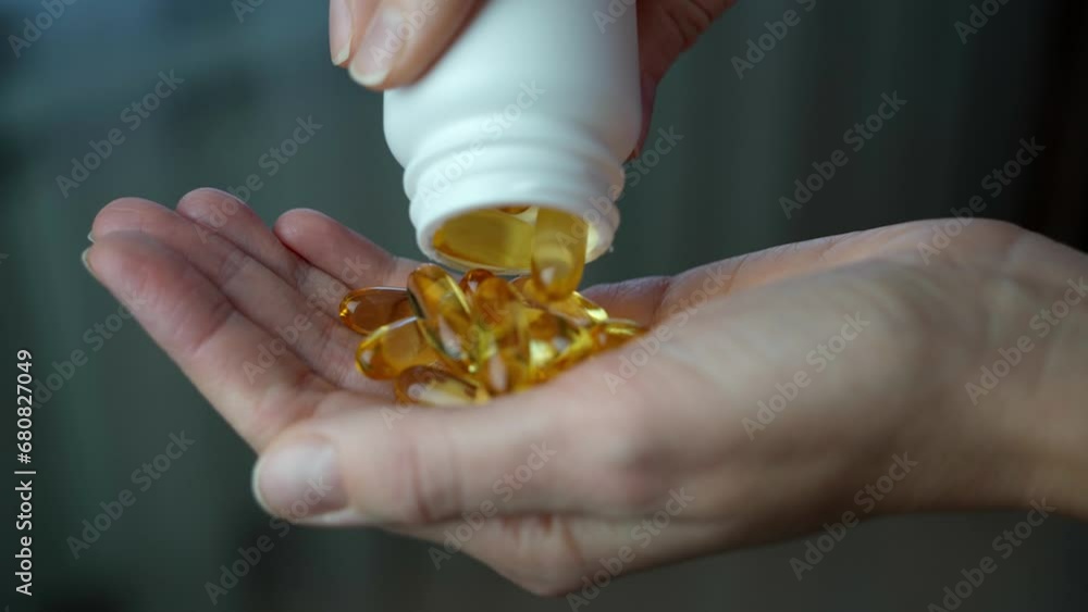 Close-up of a nutritionist's hand with omega-3 and vitamin D capsules. A female doctor pours a handful of vitamin capsules into her hand. Close-up of a nutritionist's hand with omega-3 and vitamin D capsules. A female doctor pours a handful of vitamin capsules into her hand.