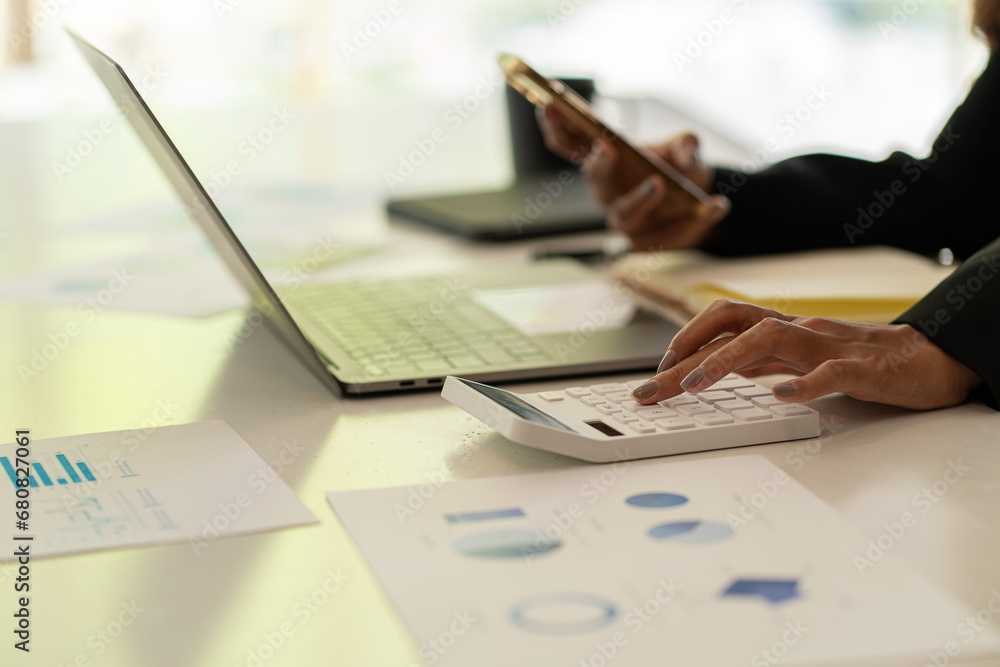 Naklejka premium Accountant counting on calculator and holding documents in hand close-up Accounting concept with laptop to do math finance on table, analytical research concept