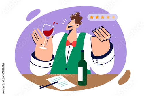 Man sommelier tastes red wine and gives five stars to alcoholic drink likes, standing near table