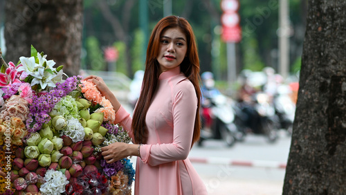 A young girl wearing a lotus pink color ao dai the traditional costume of Vietnam. Photo for tourism, culture, tradition, and the beauty of Asian people. Idea for train model in computer vision system