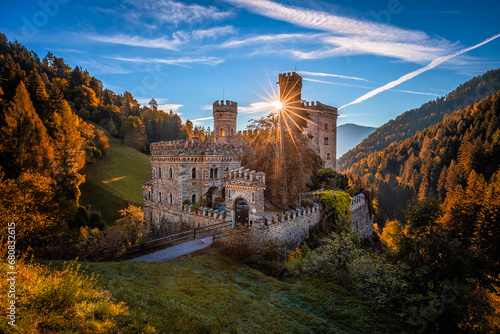 Latzfons, Italy - Beautiful autumn scenery at Gernstein Castle (Castello di Gernstein, Schloss Gernstein) at sunrise in South Tyrol with blue sky, sunrays and golden foliage photo