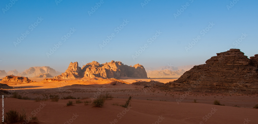 Jordan. Desert of Wadi Rum. Bizarre shapes of rocks in deserted desert. Landscape is similar to Martian landscapes. Sand is of beautiful pink color in rays of setting sun. Nature concept for design.