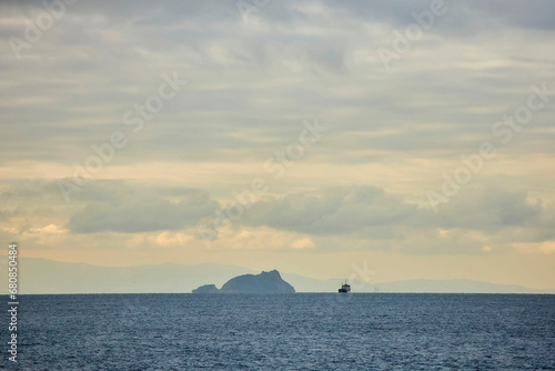 Islands in the sea or ocean and small ships at sunset. A landscape with a beautiful sky.