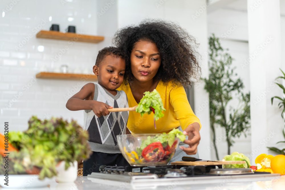 Portrait of enjoy happy love african american family mother and african little boy son child having fun help cooking food healthy eat together with fresh vegetable salad and ingredient in kitchen - obrazy, fototapety, plakaty 