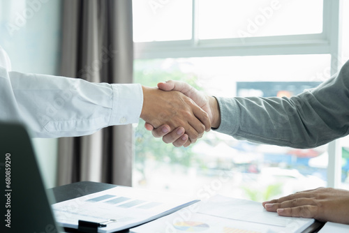 Businessmen giving handshake after working.