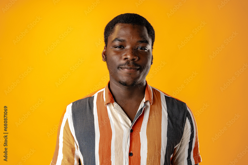 Portrait of smiling young african man in striped shirt against orange background Portrait of smiling young african man in striped shirt against orange background