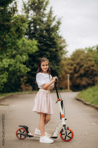 Little girl riding a kick scooter on a street near home