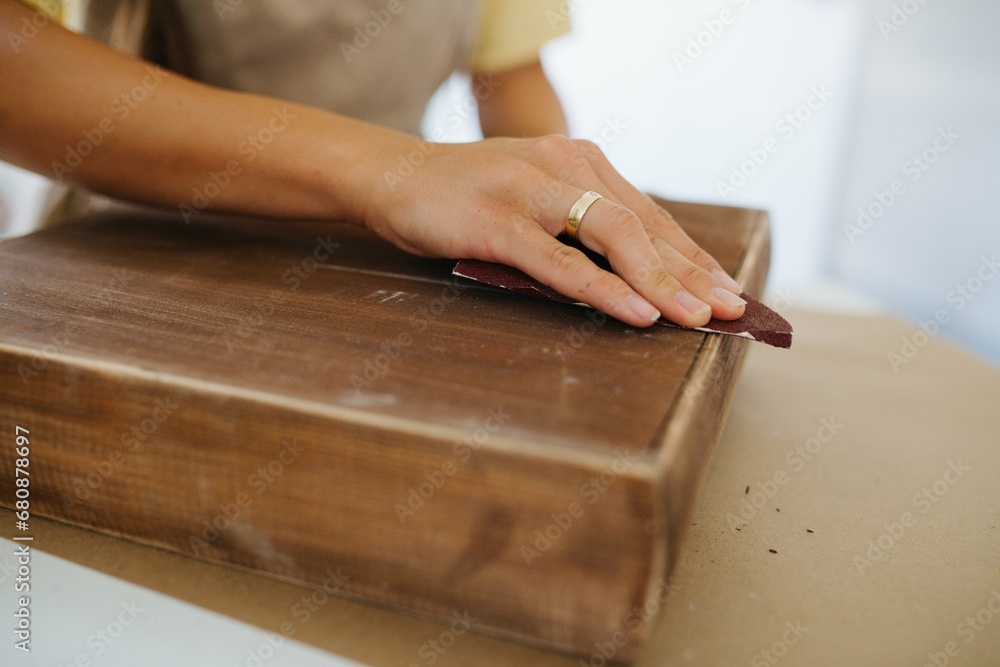 Close-up photo, craftswoman sanding a wooden surface