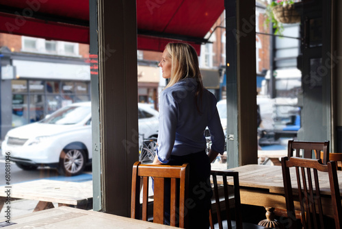 Contemplative owner looking through window at coffee shop photo