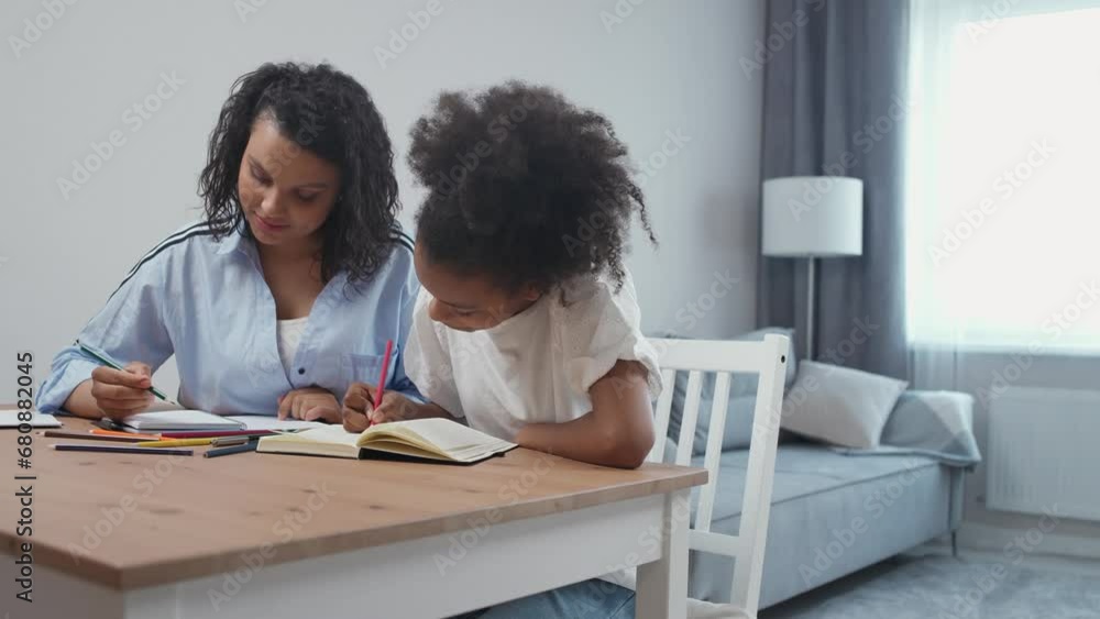 Handheld, pretty dark-skinned girl doing homework at home with her mom, draw lessons, homeschooling. Handheld, pretty dark-skinned girl doing homework at home with her mom, draw lessons, homeschooling.