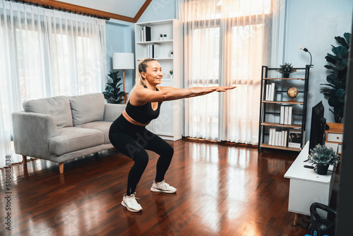 Active and fit senior woman warmup and stretching before home exercising routine at living room. Healthy fitness lifestyle concept after retirement for pensioner. Clout photo