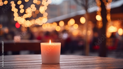 Lit up candle at an outdoor table of a restaurant in winter, cosy atmosphere, selective focus, bokeh.