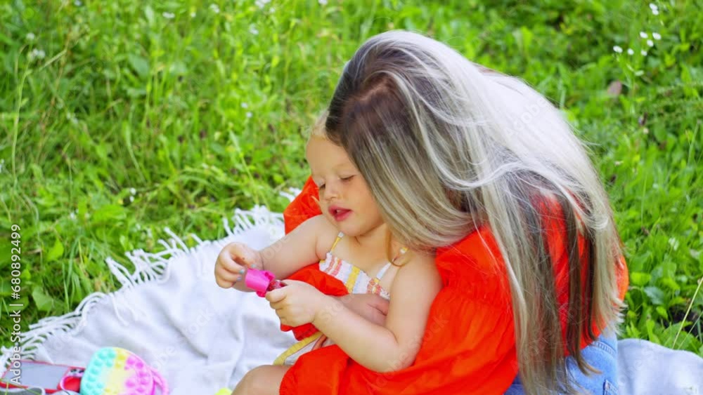 A mother hugs her daughter while sitting in a field of flowers. Concept of happy childhood and parental love for children, warmth and smiles. High quality 4k footage A mother hugs her daughter while sitting in a field of flowers. Concept of happy childhood and parental love for children, warmth and smiles. High quality 4k footage